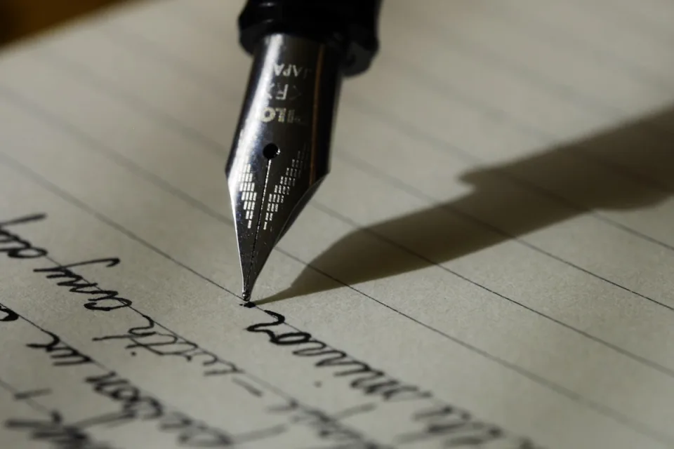Hands writing in a notebook with a fountain pen